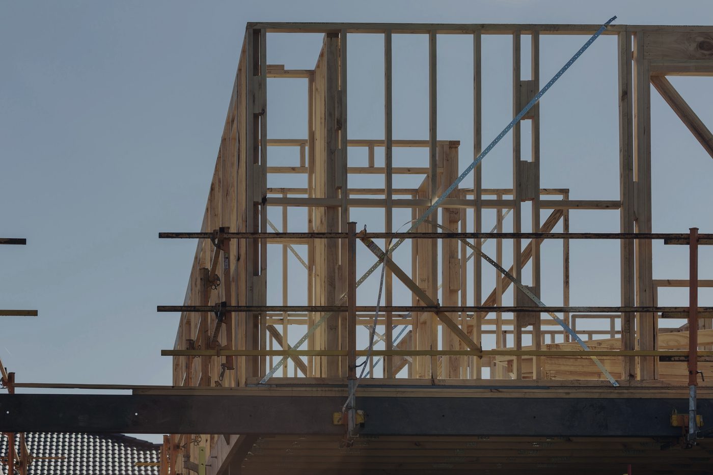 Timber house framing under construction, with scaffolding around the frame