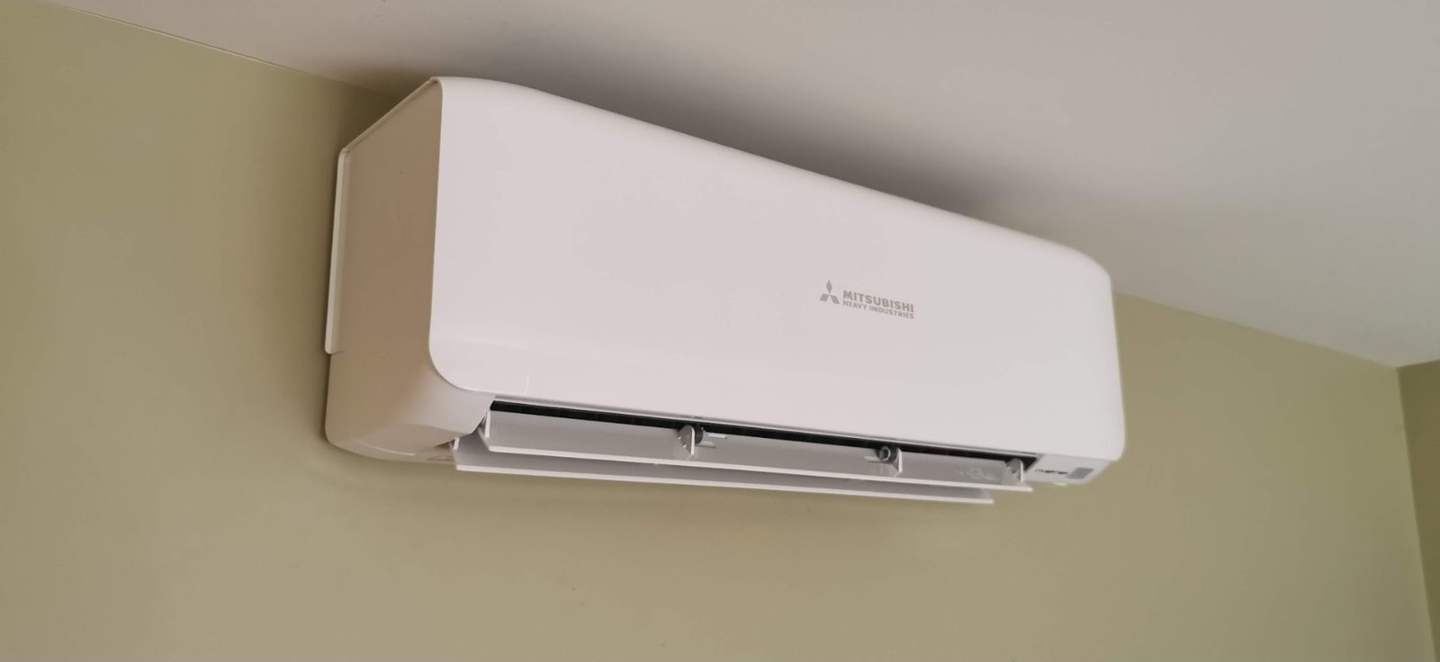 A white Mitsubishi Heavy Industries high-wall heat pump indoor unit installed on a living room wall